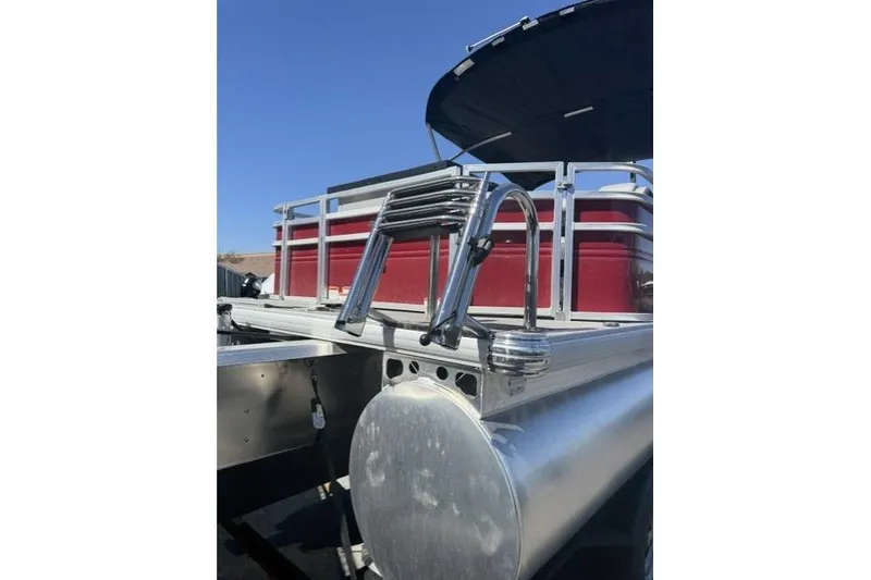 Slide: The Image of 2026 Sun Tracker Sportfish 24 XP3 pontoon boat with ladder and railing, under clear blue sky. - 2