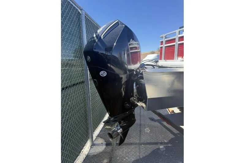 Slide: The Image of Outboard motor of 2026 Sun Tracker Sportfish 24 XP3, parked near a chain-link fence. - 9