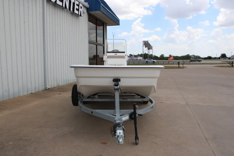 Slide: The Image of 2026 Mako Pro Skiff 19 CC boat on trailer, parked outside a building under a cloudy sky. - 1