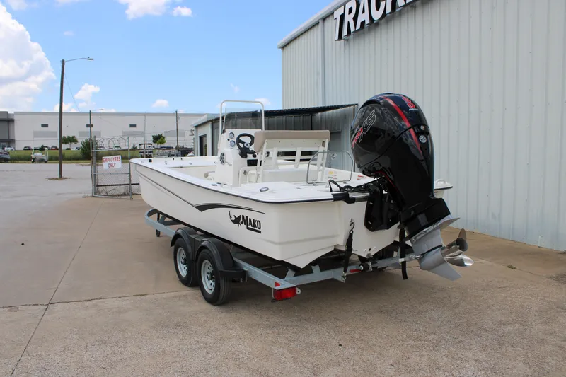 Slide: The Image of 2026 Mako Pro Skiff 19 CC boat on trailer, parked outside a warehouse. - 2