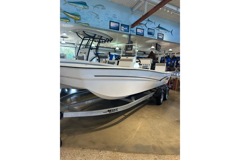 Slide: The Image of 2026 Mako Pro Skiff 19 CC boat interior with steering wheel in showroom. - 1