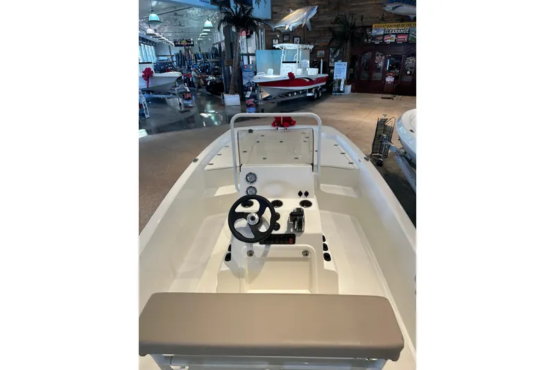 Slide: The Image of 2026 Mako Pro Skiff 19 CC boat displayed indoors on a trailer. - 2