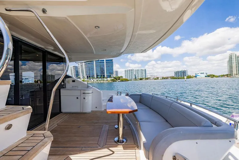 Slide: The Image of 2016 Sea Ray L650 Fly yacht deck with seating, table, and waterfront city view. - 43