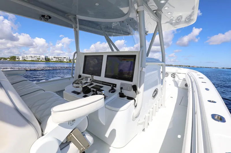 Slide: The Image of 2023 Contender 44 ST boat cockpit with dual screens, steering wheel, and ocean view. - 6