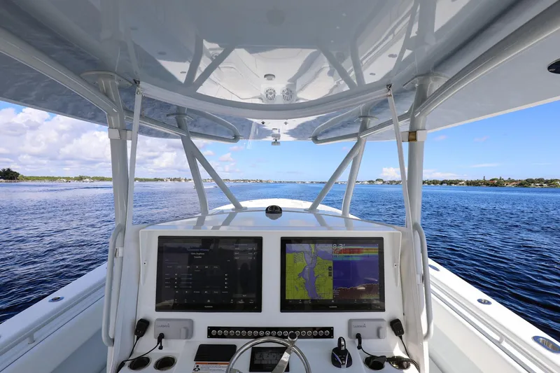 Slide: The Image of 2023 Contender 44 ST boat dashboard with dual screens, navigating on open water. - 8