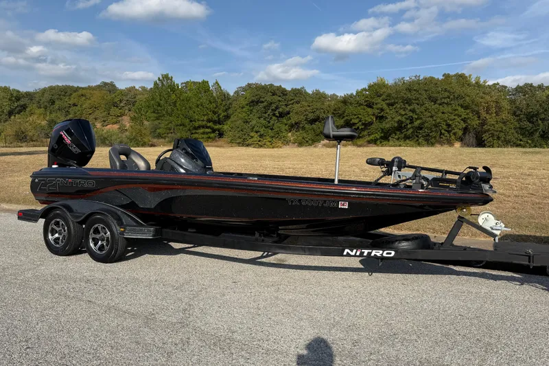 Slide: The Image of 2019 Nitro Z21 Pro bass boat on trailer, parked on a road with trees in background. - 29