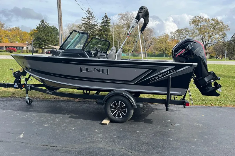 Slide: The Image of 2026 Lund 1775 Impact XS Sport boat on trailer, parked outdoors. - 2