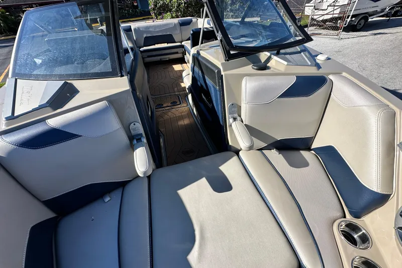 Slide: The Image of 2018 Malibu Wakesetter 23 LSV interior with beige and blue seating, cup holders, and open windshield. - 13