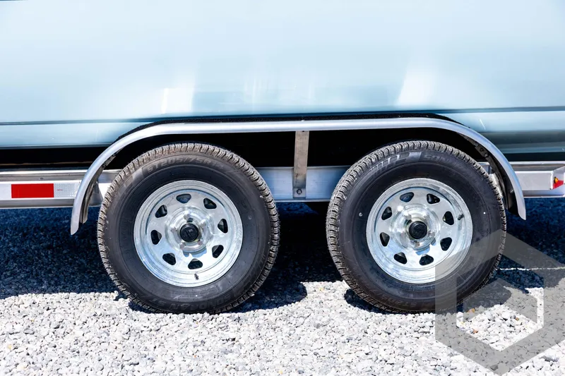Slide: The Image of Trailer wheels of a 2026 Tidewater 2110 Bay Max boat on gravel surface. - 14