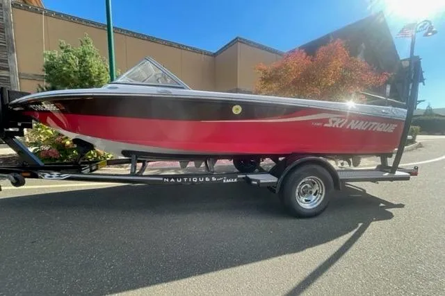 Slide: The Image of 2009 Nautique Ski Nautique 196 boat on trailer, red and black design, parked outdoors. - 1