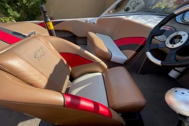Slide: The Image of 2009 Nautique Ski Nautique 196 interior with tan and red seating, steering wheel, and dashboard. - 2