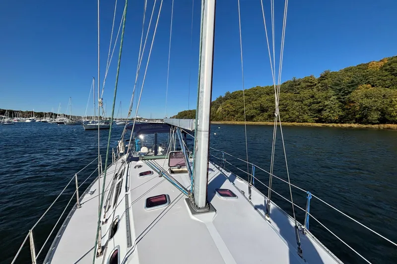 Slide: The Image of 2004 Catalina 400 MkII sailboat on calm water near a forested shoreline. - 21