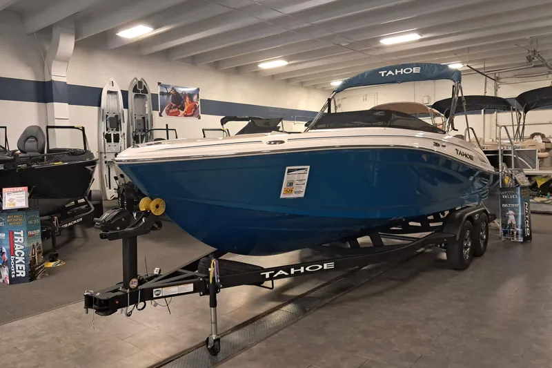 The Image of 2026 Tahoe 210 S boat in showroom, blue hull, on trailer, indoor display. - 1