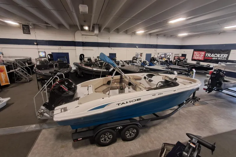 Slide: The Image of 2026 Tahoe 210 S boat displayed in a showroom with other boats. - 2