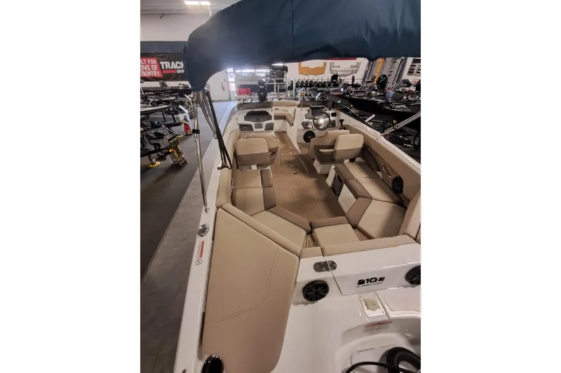 Slide: The Image of 2026 Tahoe 210 S boat interior with beige seating and canopy in showroom. - 5