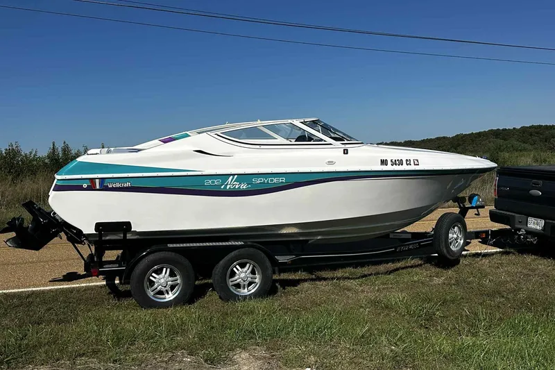 The Image of 1993 Nova Spyder boat on trailer, parked roadside under clear blue sky. - 0