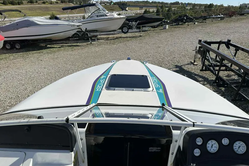 Slide: The Image of 1993 Nova Spyder boat parked on gravel lot with other boats in background. - 10