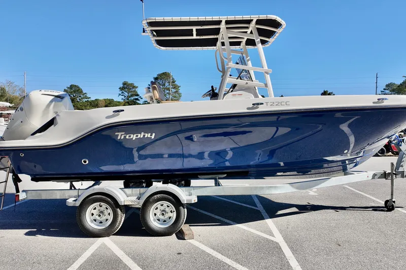 Slide: The Image of 2026 Bayliner Trophy T22CC boat on trailer, parked in a lot under clear blue sky. - 2
