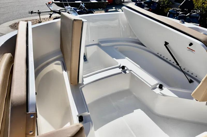 Slide: The Image of 2026 Bayliner Trophy T22CC boat interior with open storage compartments and beige seating. - 6