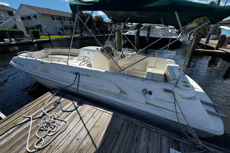 Slide: The Image of 1996 Sea Ray 240 Sundeck boat docked, featuring green canopy and sleek design. - 25