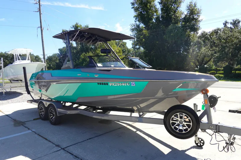 Slide: The Image of 2022 Axis T23 boat on trailer, teal and gray design, parked outdoors. - 3