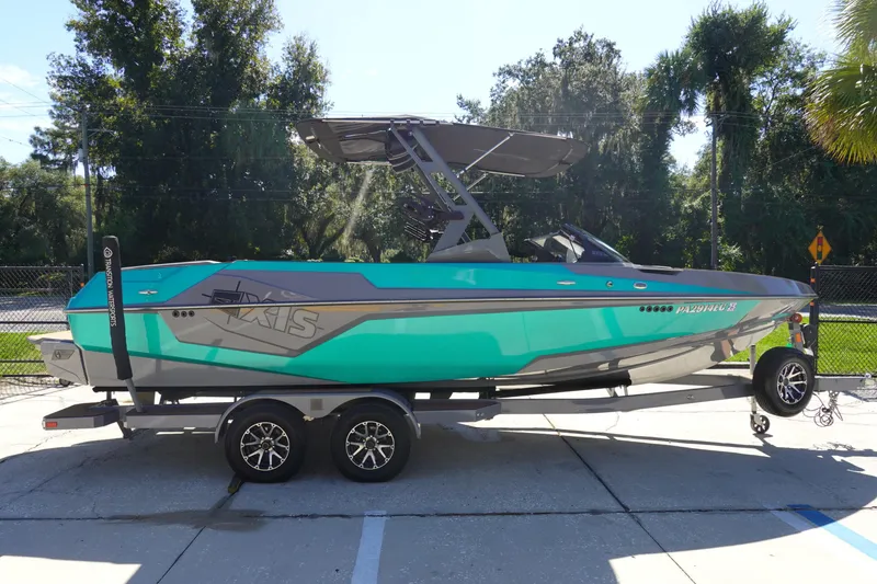 Slide: The Image of 2022 Axis T23 boat on trailer, teal and gray design, parked outdoors. - 4