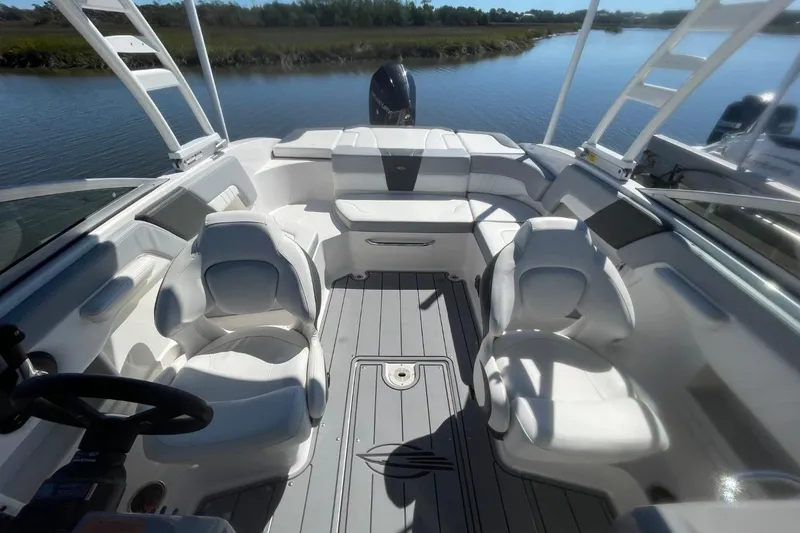 Slide: The Image of 2022 Chaparral 23 SSi boat interior with white seating and sleek design on calm water. - 16