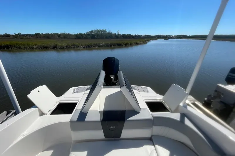Slide: The Image of 2022 Chaparral 23 SSi boat on calm water, featuring sleek seating and storage compartments. - 17