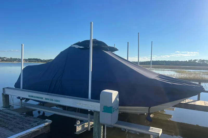 Slide: The Image of 2022 Chaparral 23 SSi boat covered on a lift by a serene lake. - 2