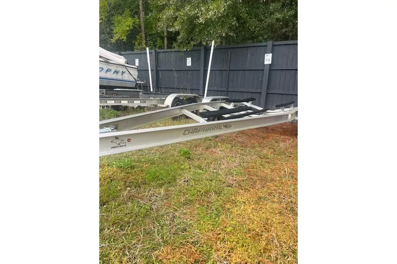 Slide: The Image of 2022 Chaparral 23 SSi boat trailer parked on grass near a black fence. - 20