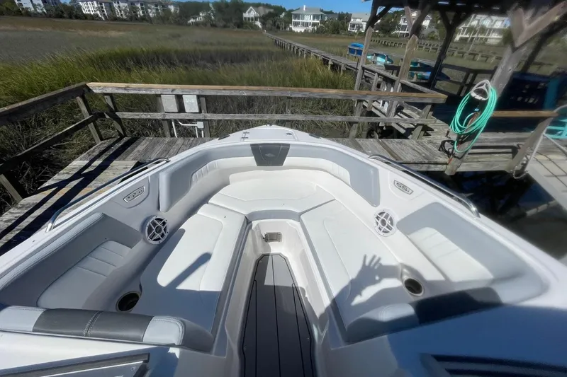 Slide: The Image of 2022 Chaparral 23 SSi boat interior with white seating, docked near wooden pier. - 5