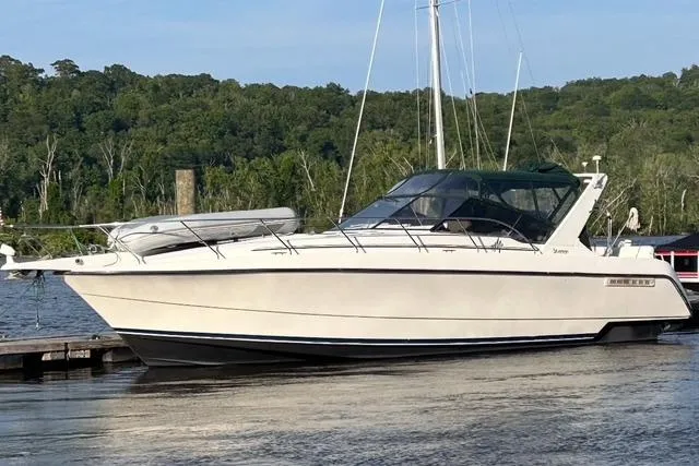 The Image of 1993 Silverton Express boat docked on a calm river with lush green trees. - 1