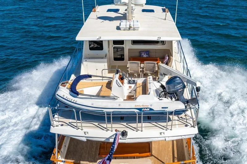 Slide: The Image of 2015 Marlow 66E-CB yacht cruising on open water with a small boat on deck. - 5