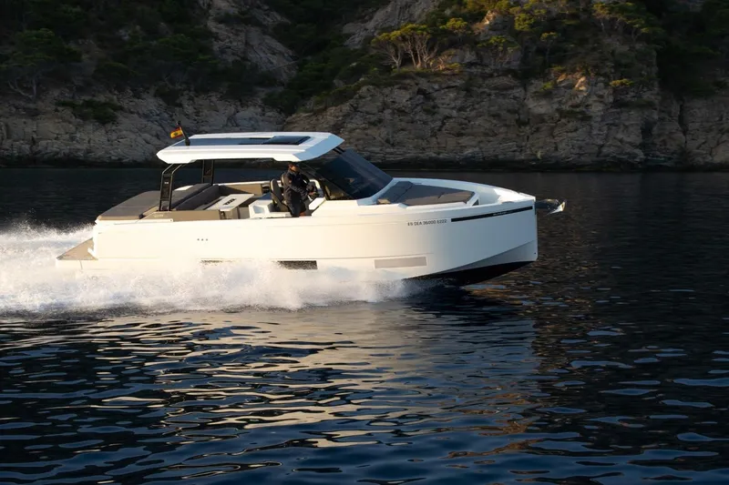 Slide: The Image of 2026 De Antonio Yachts D36 cruising on calm waters near rocky coastline. - 4