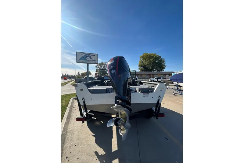 Slide: The Image of 2026 Lund 1875 Impact XS Sport boat on trailer, covered, in sunny outdoor setting. - 14