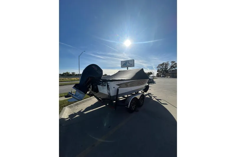 Slide: The Image of 2026 Lund 1875 Impact XS Sport boat on trailer, covered, under clear blue sky. - 8