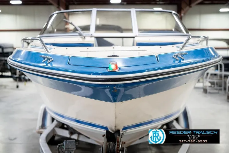 Slide: The Image of 1987 Sea Ray Sorrento 21 boat in showroom, blue and white exterior, front view. - 4
