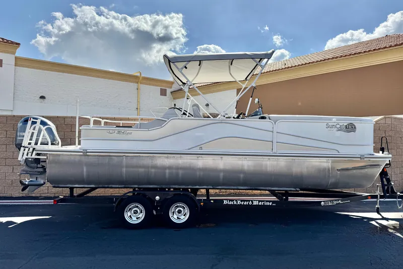 The Image of 2020 SunCatcher V24 SS pontoon boat on trailer, parked outdoors under a blue sky. - 0