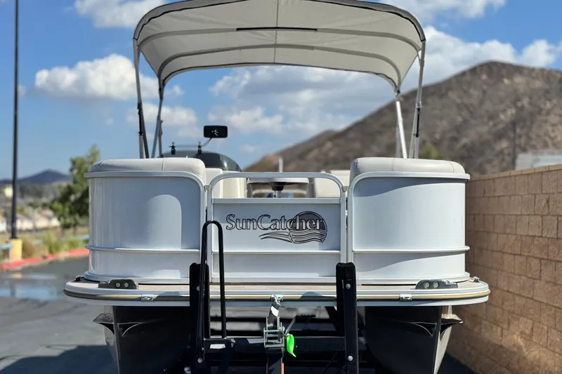 Slide: The Image of 2020 SunCatcher V24 SS pontoon boat with canopy, parked outdoors under blue sky. - 2