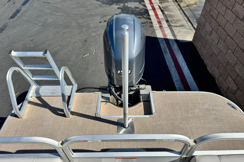 Slide: The Image of 2020 SunCatcher V24 SS pontoon boat with motor and ladder, parked on pavement. - 21