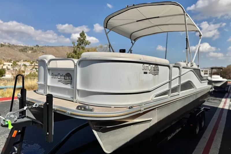 Slide: The Image of 2020 SunCatcher V24 SS pontoon boat with canopy on trailer, set against a scenic backdrop. - 3