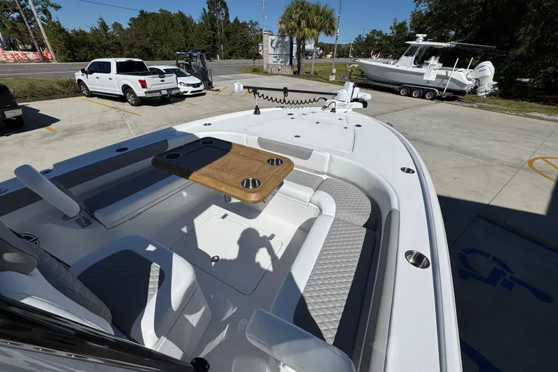 Slide: The Image of 2026 Caymas 26 HB boat with seating and table, parked outdoors. - 17
