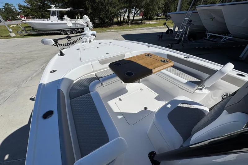 Slide: The Image of 2026 Caymas 26 HB boat interior with seating and wooden table, docked outdoors. - 19