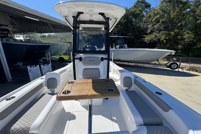 Slide: The Image of 2026 Caymas 26 HB boat interior with seating and table, parked outdoors. - 21