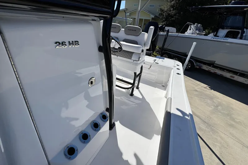 Slide: The Image of 2026 Caymas 26 HB boat interior with seating and rod holders, docked outdoors. - 22