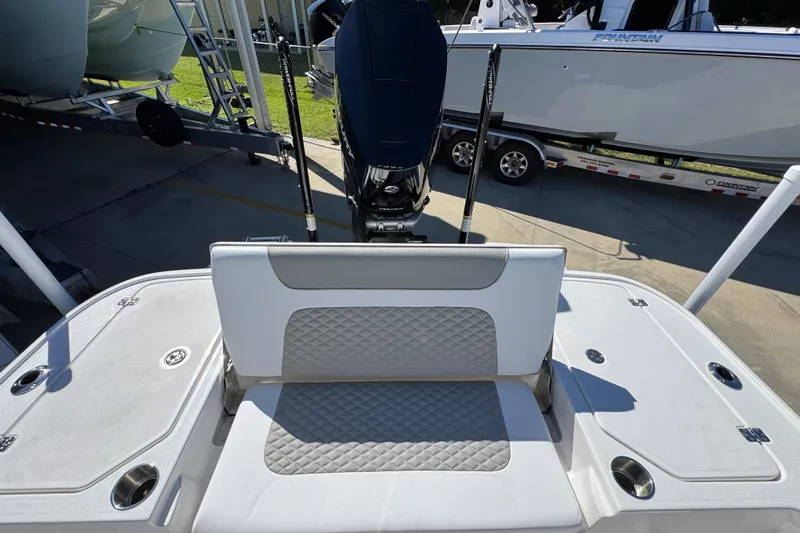 Slide: The Image of 2026 Caymas 26 HB boat with cushioned seating and outboard motor in a marina setting. - 33