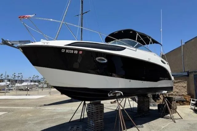 Slide: The Image of 2010 Bayliner 255 Cruiser on stands, black and white hull, marina background. - 11
