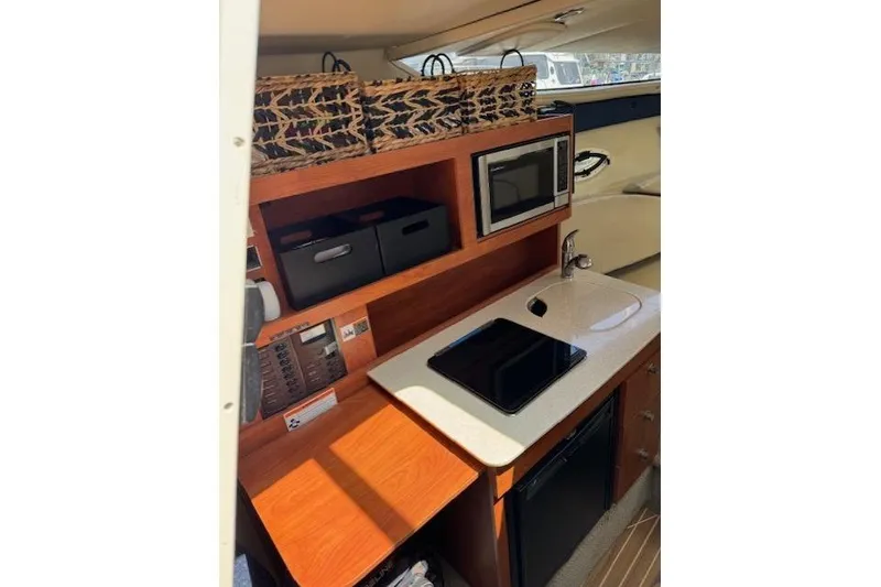 Slide: The Image of 2010 Bayliner 255 Cruiser interior kitchen with microwave, sink, and storage baskets. - 18