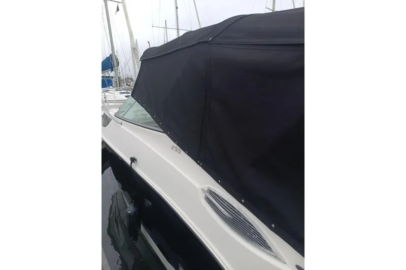 Slide: The Image of 2010 Bayliner 255 Cruiser with black canopy docked at marina. - 31