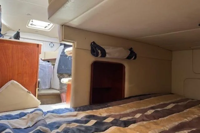 Slide: The Image of Interior cabin of 2010 Bayliner 255 Cruiser with striped bedding and wooden accents. - 33